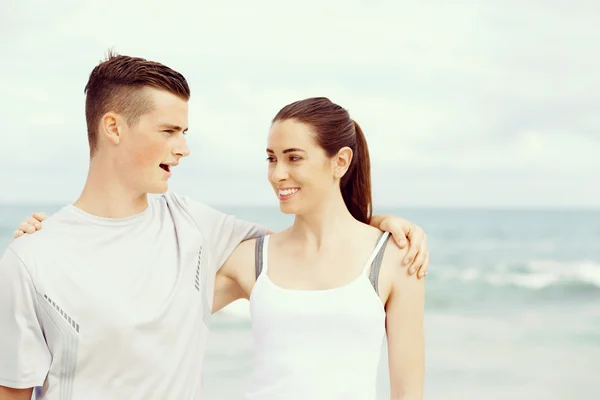 Young couple looking at each other while standing on beach — Stock Photo, Image