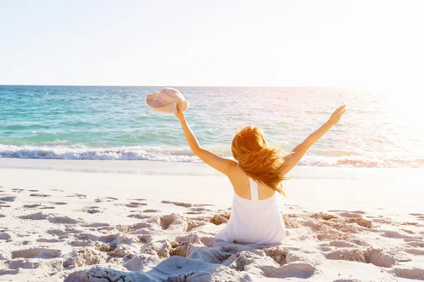 Jonge vrouw zittend op het strand — Stockfoto