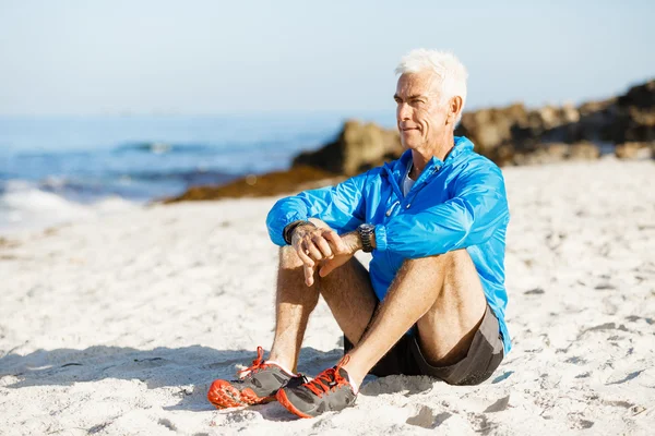 Mann in Sportkleidung sitzt am Strand — Stockfoto