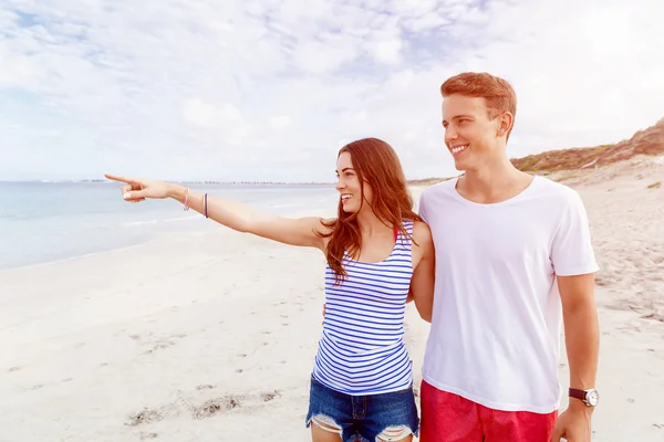 Gelukkige jonge man en vrouw paar samen wandelen op een strand — Stockfoto