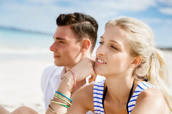 Romantische jonge paar zittend op het strand — Stockfoto