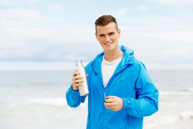 Şişe su ile tutarak kendine güvenen genç adam