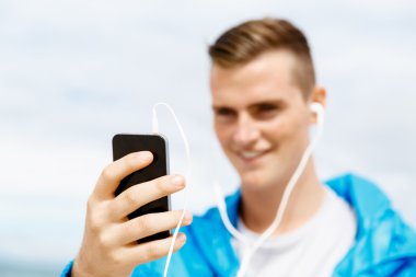 Erkek runner mobil akıllı telefonunu açık havada duran ile