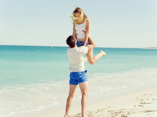 Casal feliz pulando em férias na praia — Fotografia de Stock