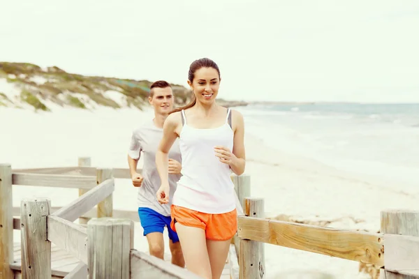 Des coureurs. Jeune couple courant sur la plage — Photo