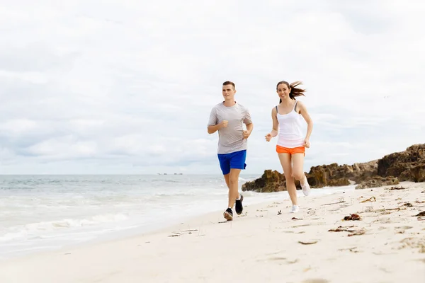 Des coureurs. Jeune couple courant sur la plage — Photo