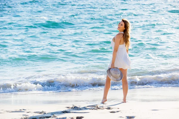 Jeune femme marchant le long de la plage — Photo