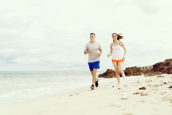 Des coureurs. Jeune couple courant sur la plage — Photo