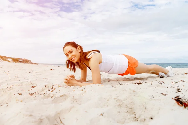 Mujer joven entrenando en la playa afuera — Foto de Stock