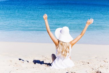 Genç bir kadın sahilde dinleniyor.