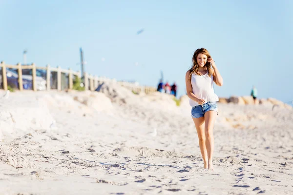 Młoda kobieta spacerująca wzdłuż plaży — Zdjęcie stockowe