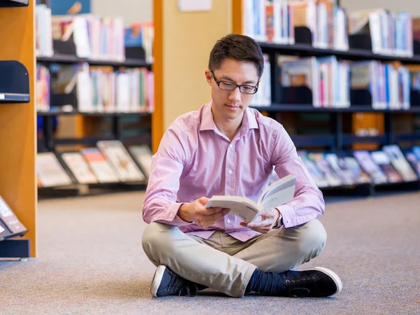 Estudante do sexo masculino feliz segurando livros na biblioteca — Fotografia de Stock