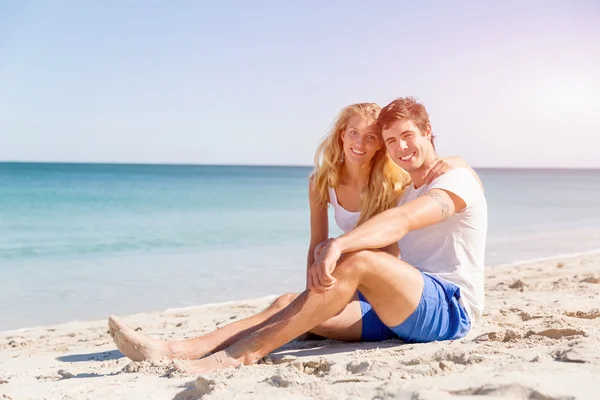 Romantique jeune couple assis sur la plage — Photo