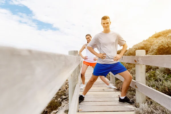 Läufer. junges Paar beim Turnen und Stertching am Strand — Stockfoto