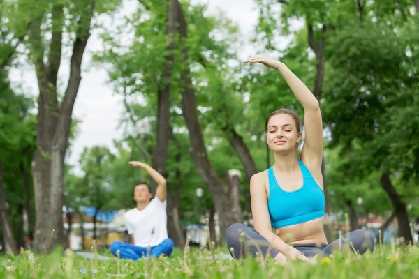 Genç çift yeşil çimenlerin üzerinde meditasyon — Stok fotoğraf