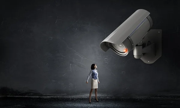 Junge Frau im Zimmer unter Kontrolle der Videokamera — Stockbild Kamera behält Frau im Auge — Stockfoto