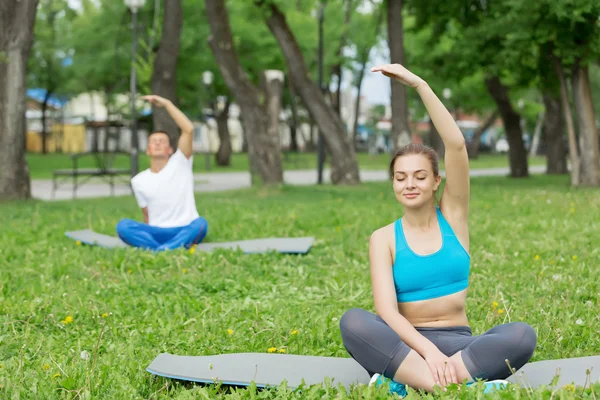 Genç çift yeşil çimenlerin üzerinde meditasyon — Stok fotoğraf