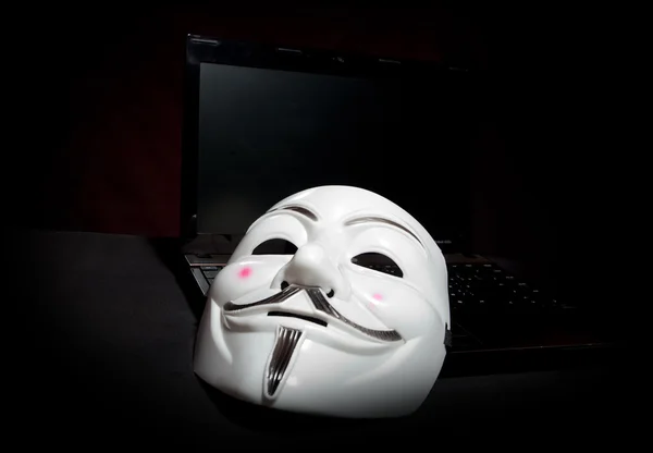 Anonieme masker donkere over laptop — Stockfoto