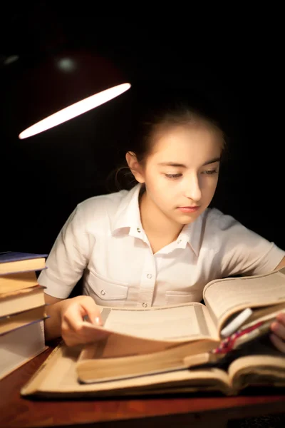 Jovencita leyendo libro por la noche oscuro en la biblioteca — Foto de Stock