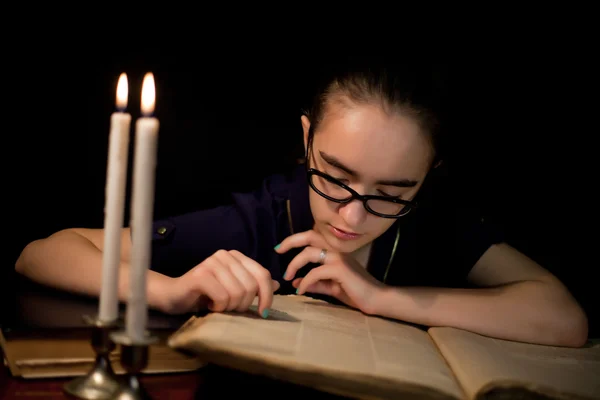 Girl reading book in dark library — Stock Photo, Image