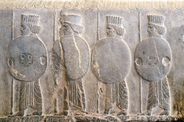 Mızrakları ve kalkanları olan Asurlu savaşçılarla dolu eski bir duvar, Persepolis, İran. UNESCO dünya mirası sahası
