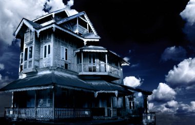 Perili ev. Gece gökyüzü arka planında terk edilmiş eski bir ev. Gizemli bir arazide korkunç bir koloni kulübesi. Fotoğraf mavi tonda.
