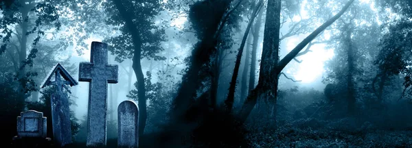 Horizontal banner with night nature scene. Mysterious landscape with Halloween scene with medieval stone crosses, tombstones in a cemetery in foggy forest. Photo toned in blue color