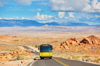 School bus driving on winding road in Valley of the Fire national park clipart