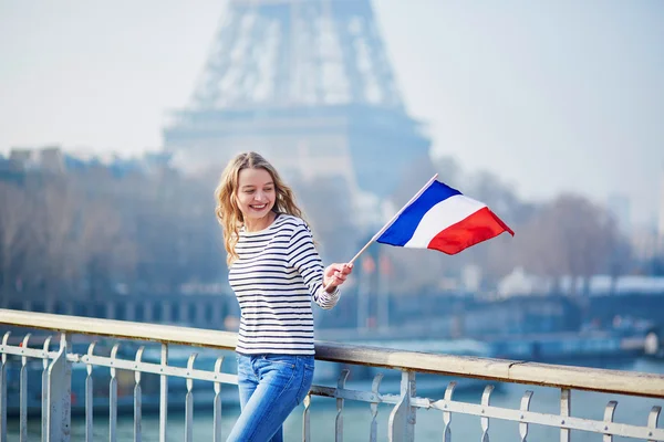 Hermosa joven con bandera nacional francesa cerca de la torre Eiffel —  Fotos de Stock