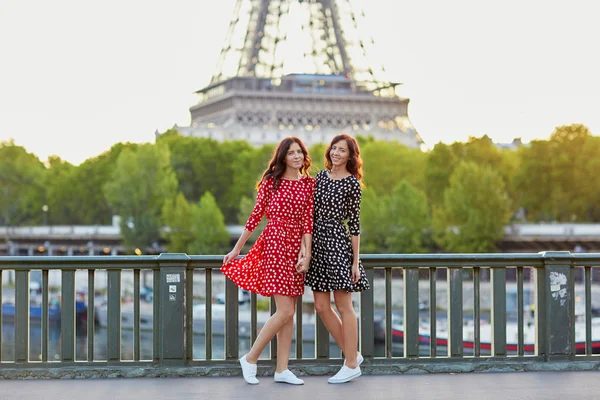 Beautiful twin sisters in front of the Eiffel tower in Paris — Stock Photo, Image