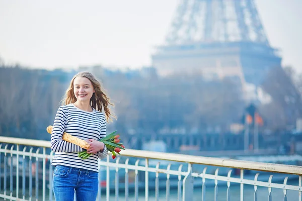 Dívka s tradiční francouzskou bagetou a tulipány — Stock fotografie