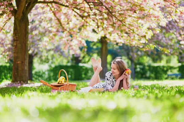 桜の庭でピクニックを持つ少女 — ストック写真