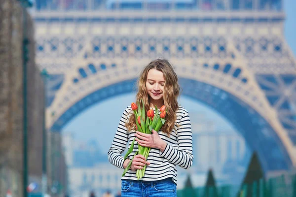 Menina com um monte de tulipas vermelhas perto da torre Eiffel — Fotografia de Stock