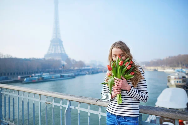 Chica con manojo de tulipanes rojos cerca de la torre Eiffel — Foto de Stock