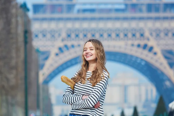 Ragazza con baguette tradizionale francese vicino alla torre Eiffel — Foto Stock