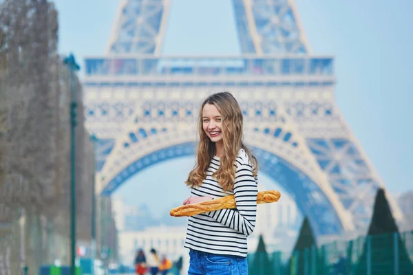Menina com baguete tradicional francesa perto da torre Eiffel — Fotografia de Stock