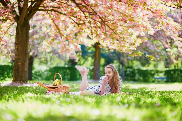 Schöne junge Frau beim Picknick im blühenden Frühlingspark — Stockfoto
