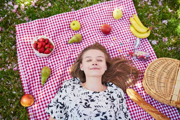 Beautiful young woman having picnic in park