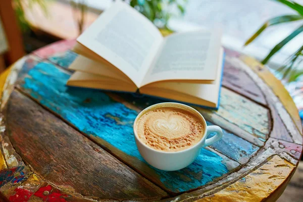 Cup of coffee and book on a wooden table