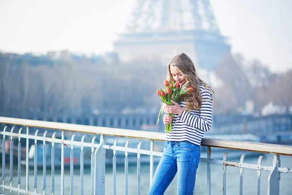 Menina com um monte de tulipas vermelhas perto da torre Eiffel — Fotografia de Stock