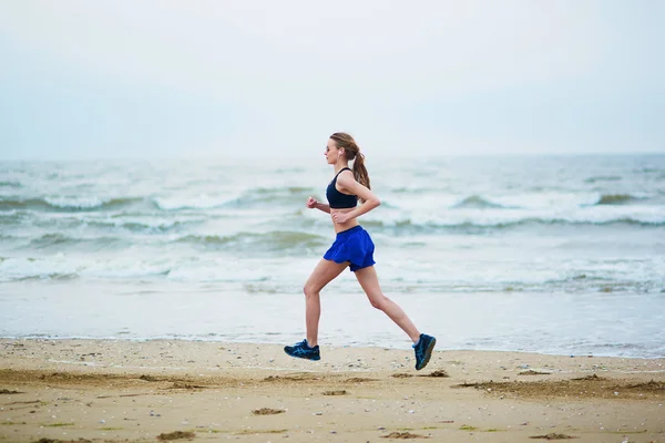 Young fitness running woman jogging on beach — Stock Photo, Image