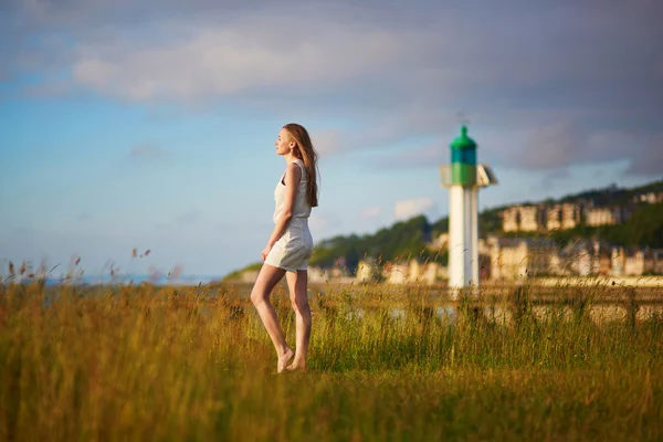 Junge Frau bei Sonnenuntergang auf Wiese in der Nähe des Leuchtturms — Stockfoto