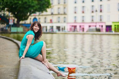 renkli kağıt tekne üzerinde Canal Saint Martin, Paris, Fransa ile oynayan kadın