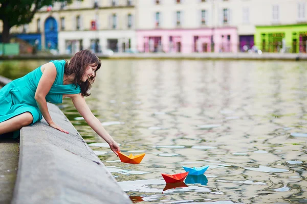 Kobieta gra na kolorowe papierowe łódki na Canal Saint Martin w Paryżu — Zdjęcie stockowe