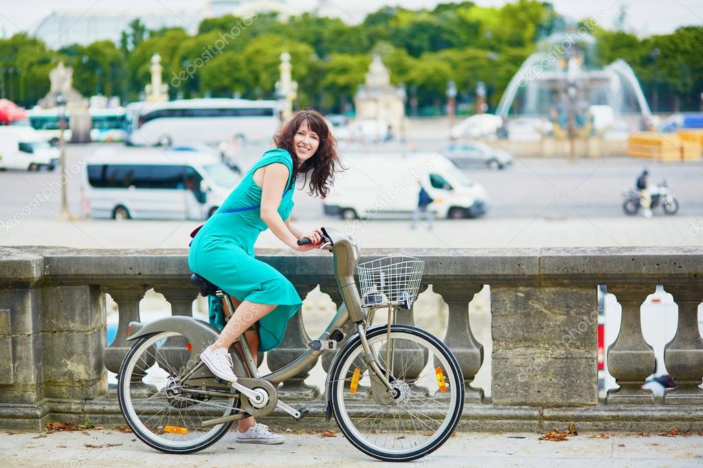 Schöne junge Frau auf einem Fahrrad auf einer Straße von