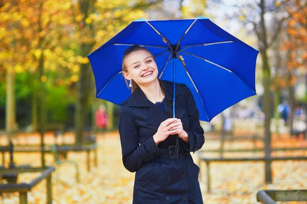 Young woman with blue umbrella in the Luxembourg garden of Paris on a fall or spring rainy day — Stock Photo, Image