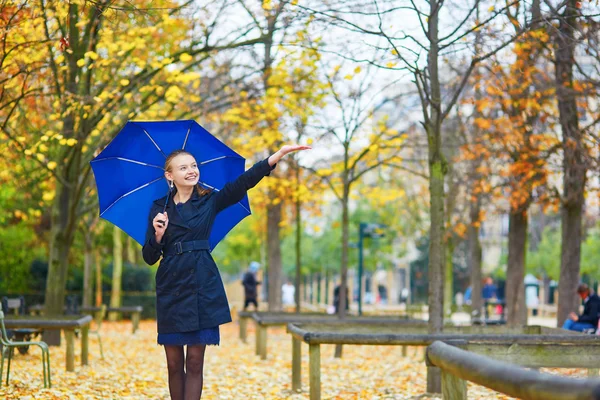 Young woman with blue umbrella in the Luxembourg garden of Paris on a fall or spring rainy day — Stock Photo, Image