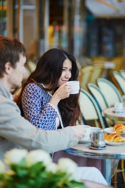 Pareja bebiendo café y comiendo croissants en café parisino —  Fotos de Stock