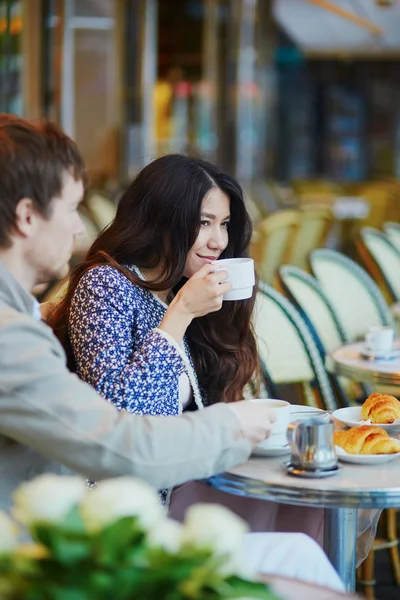 Pareja bebiendo café y comiendo croissants en café parisino — Foto de Stock