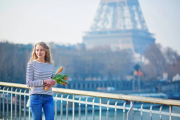 Chica con baguette tradicional francesa y tulipanes — Foto de Stock